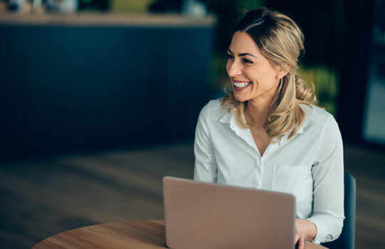 Woman sitting working at laptop smiling