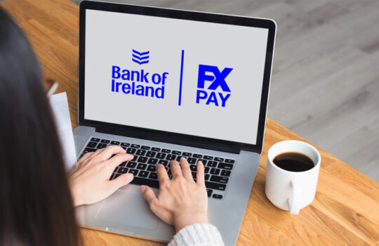 Woman using a computer with as background the Logo of Bank Of Ireland